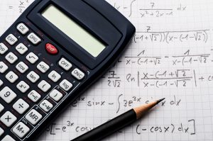 calculator and pencil laying on an open math textbook